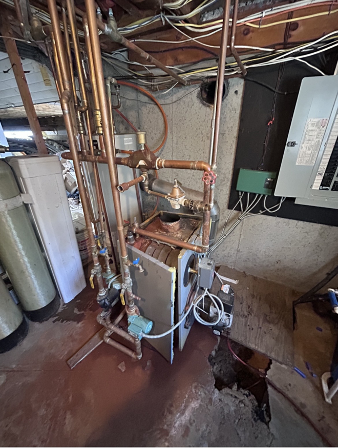 An old boiler heating system with extensive copper piping and pumps, undergoing repair or maintenance by HomeStyle Heating and Air LLC in Barrington, NH.