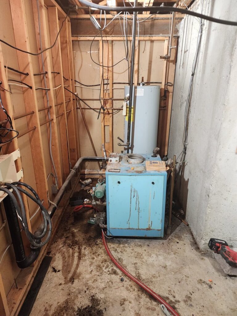 An old boiler and water heater in a utility room, ready for service or replacement by D & D Heating & Air in Brighton, CO.