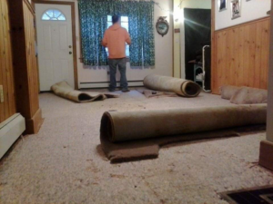 Old carpet being removed from a room, demonstrating carpet removal services by Knights Flooring in South Portland, ME.