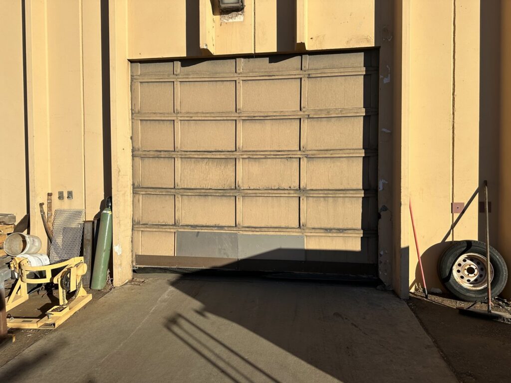 An old, dirty commercial garage door in need of repair or replacement by Strongdoor garage in Denver, CO.
