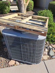 An old, damaged outdoor AC unit on the ground after removal by ASAP Air Conditioning and Heating in Mesa, AZ.
