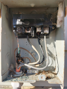 An old and damaged electrical disconnect box with exposed wiring, showing a repair need by Devin Parker Electric in Knoxville, TN
