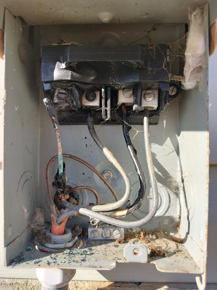 An old and damaged electrical disconnect box with exposed wiring, showing a repair need by Devin Parker Electric in Knoxville, TN