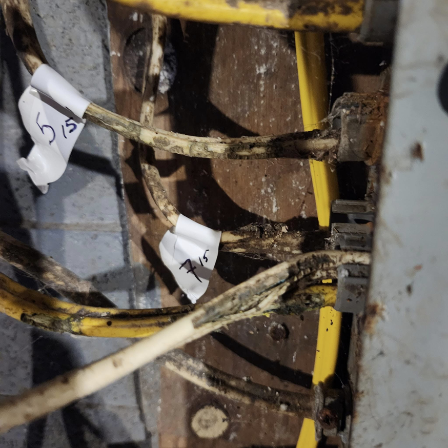 Close-up of old and potentially damaged electrical wires with labels, indicating a need for inspection or repair by SEL Electric in Truro, NS.