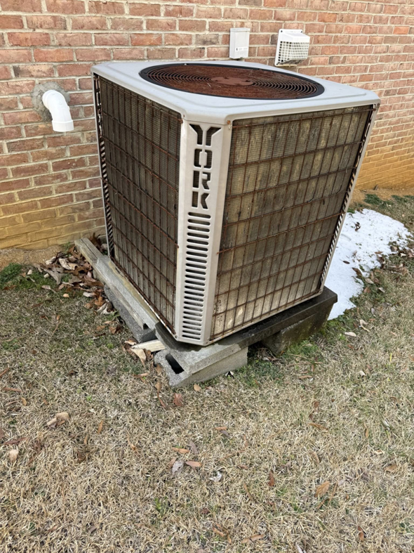 An old and dirty outdoor HVAC condenser unit, showing the need for service from On-Target Heating & Air LLC in Rock Hill, SC.