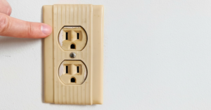 An old, discolored electrical outlet, ready for inspection or replacement by Airhart Electric, Inc. in Coventry, RI