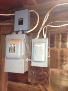 Old electrical panels and wiring on a wooden wall, serviced by Boweaks Electrical Solution LLC in Honolulu, HI.