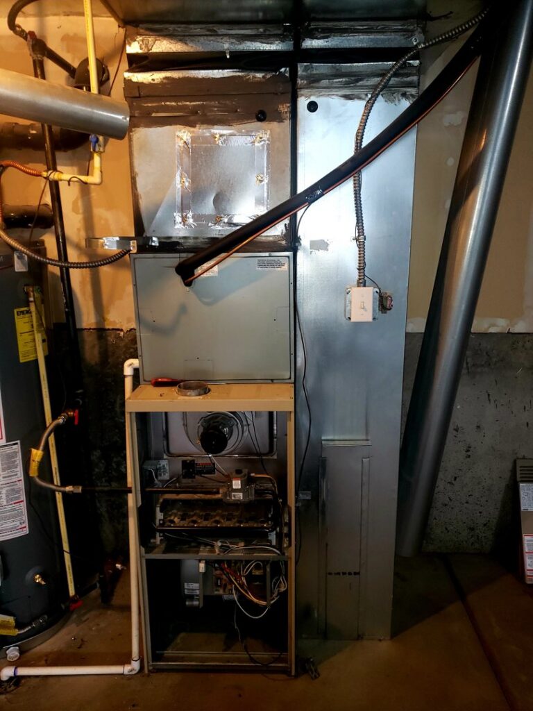 An old furnace and air handler with an open panel during an inspection by Thin Air Heating & Cooling Repair in Arvada, CO.