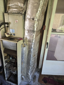 An older furnace and air handler unit with exposed components being serviced by Jesse's HVAC LLC in Newport News, VA.