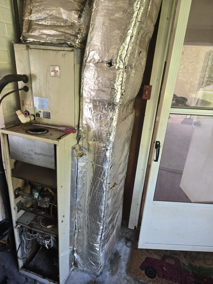 An older furnace and air handler unit with exposed components being serviced by Jesse's HVAC LLC in Newport News, VA.