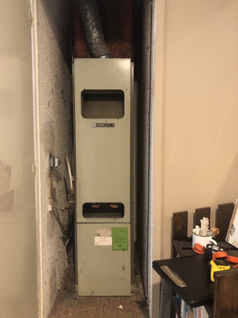 An old furnace or air handler unit located in a utility closet, indicating potential HVAC replacement work by Peace & Comfort Heating and Air in San Diego, CA.