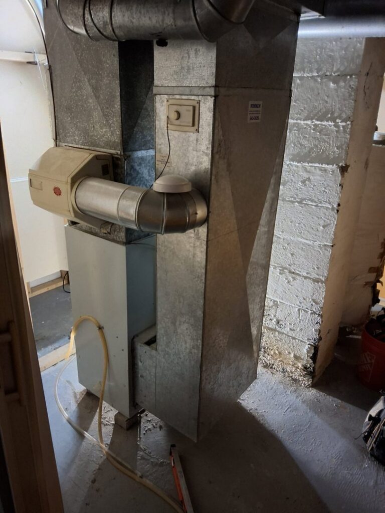 An older furnace with an attached humidifier, showing existing HVAC equipment by Nimmer Heating & Air Conditioning in Milwaukee, WI