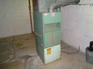 An old green furnace and HVAC unit located in a basement, serviced by Collins Cooling and Heating in Cleveland, OH.