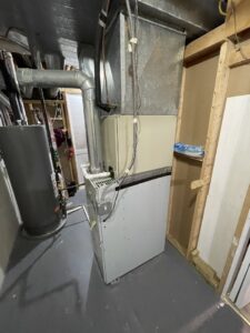 An older furnace unit with exposed components, likely undergoing inspection or repair by Adam's HVAC in Naperville, IL.