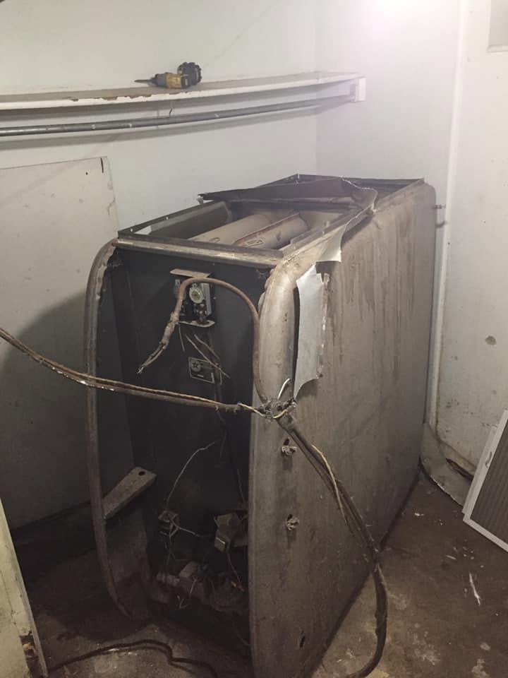 An old furnace unit partially disassembled for replacement or major repair by ICare Heating & Air in Millcreek, UT.