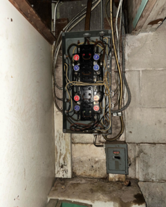 An old fuse box or electrical panel with complex wiring, indicating an upgrade or repair by Elite Electric in Valley Falls, NY