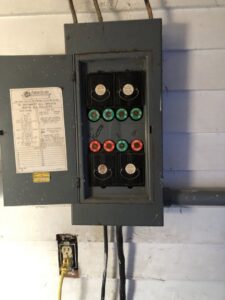 An old fuse box with various fuses and an electrical outlet, showing electrical service work by Affordable Electric, LLC in Kearney, NE.