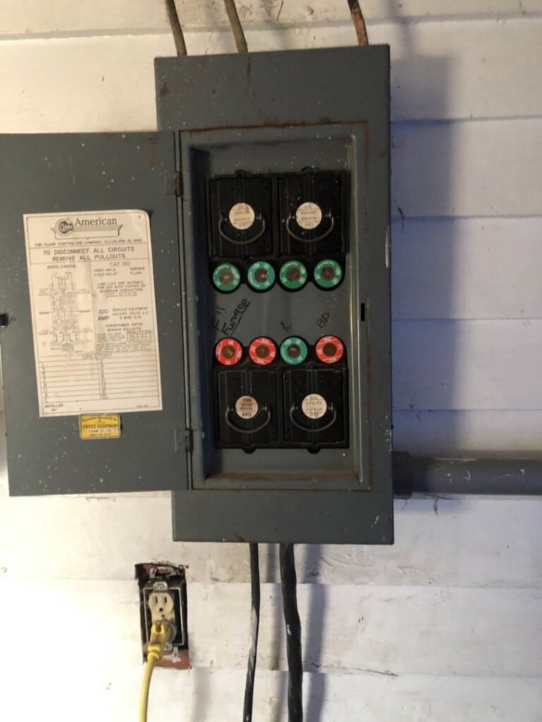 An old fuse box with various fuses and an electrical outlet, showing electrical service work by Affordable Electric, LLC in Kearney, NE.