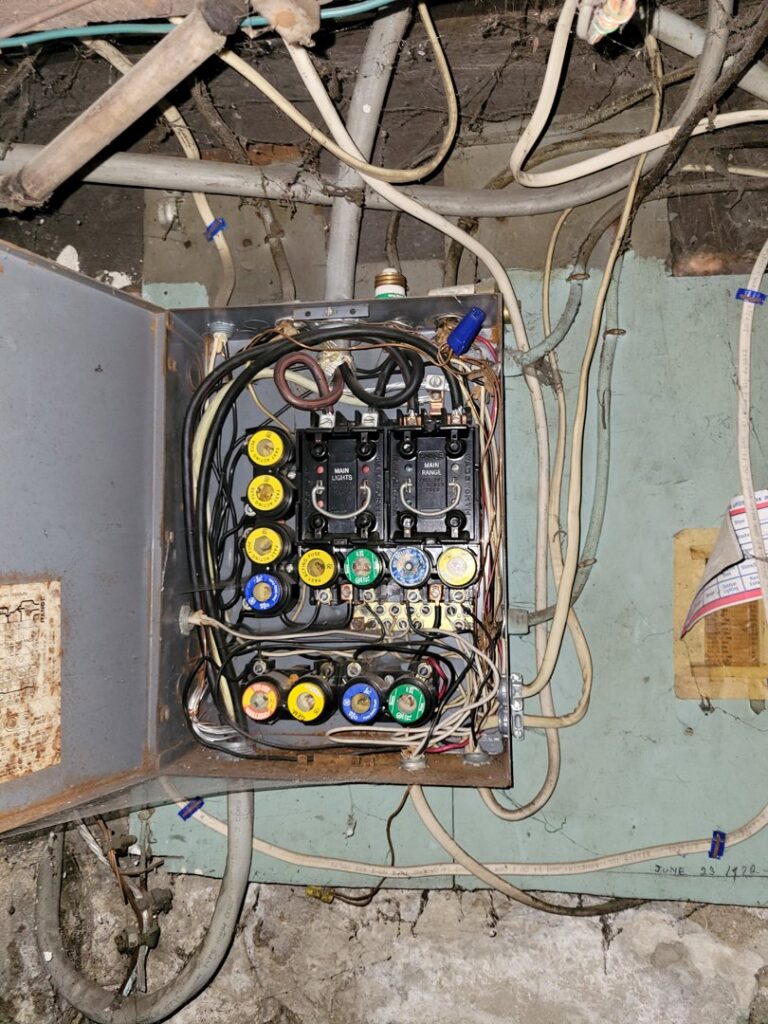 An old, open fuse box with various fuses and wiring, indicating a need for inspection or upgrade by Maiolo Electric in Pittsburgh, PA.