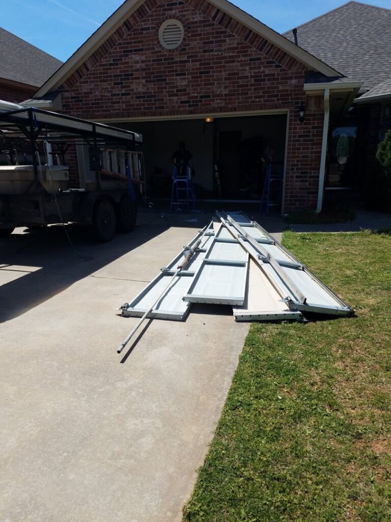 Old garage door panels and tracks laid out on a driveway during a replacement by Garage Door Specialists Of Oklahoma Inc. in Midwest City, OK.