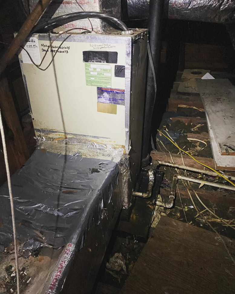 An old and dirty HVAC air handler unit located in an attic, showing a system in need of service from Comfort Pros in Mobile, AL.