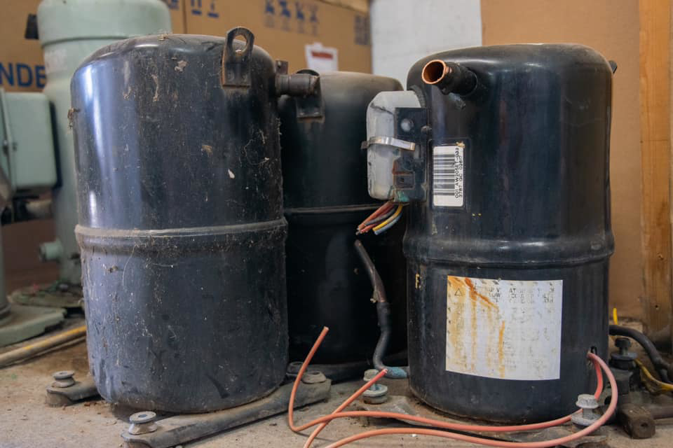 Old HVAC compressors, likely awaiting replacement or disposal by AirTemp Heating & Cooling in Nashville, TN.