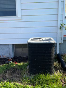 An older, weathered outdoor HVAC condenser unit next to a home, serviced by SJ Conner and Sons Inc in Roanoke, VA