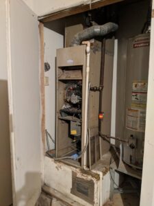 An older HVAC furnace unit with an open access panel, ready for inspection or service by Goodpaster's Mechanical, Inc. in Broken Arrow, OK.