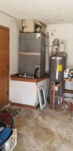 An old indoor HVAC air handler unit and water heater, showing existing equipment in Alexandria, VA.