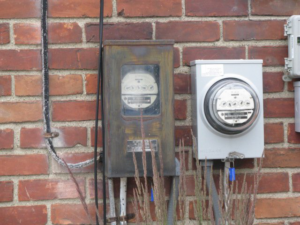 An old and a new electric meter installed on a brick wall by Mac Electric Company in Warren, MI.