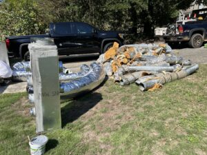 A pile of old and new HVAC ductwork on a lawn, indicating a duct replacement job by Underwood Heating and Air Conditioning in Phenix City, AL