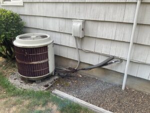 An older outdoor HVAC unit next to a residential building, ready for service or replacement by Gresham Heating and Air Conditioning in Wood Village, OR.