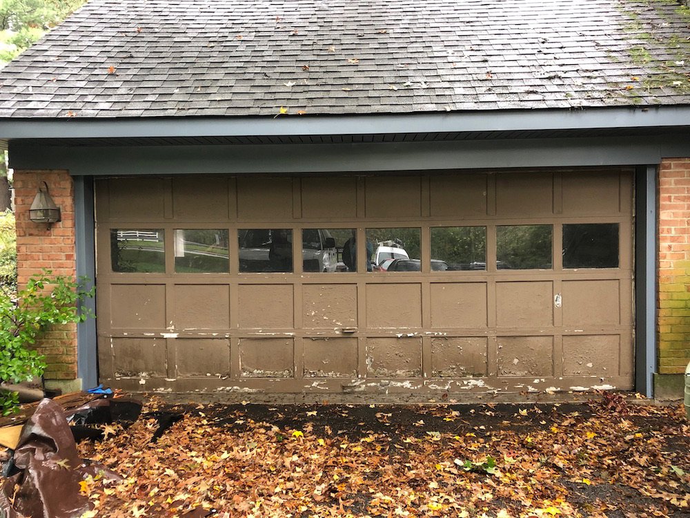 An old, peeling brown garage door with multiple windows, showing a before-replacement scenario by Door-Tech LLC in Lexington, KY.