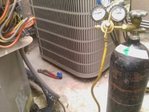 An old, removed HVAC compressor unit, showing wear and tear, replaced by J AND J HVAC L.L.C in Mesa, AZ