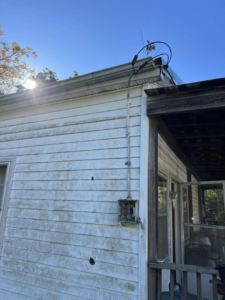Old residential electrical service entry with exposed wiring and conduit on the side of a house, showing potential work for RJ Boyd Electric in Christiansburg, VA.