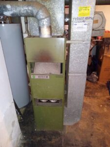 Old Rheem furnace and ductwork in a basement, ready for replacement by Breyer's Heating & Air Conditioning in Belleville, MI