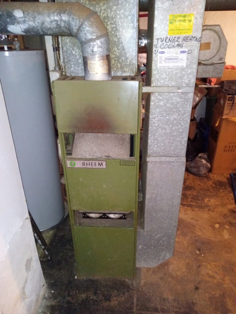 Old Rheem furnace and ductwork in a basement, ready for replacement by Breyer's Heating & Air Conditioning in Belleville, MI