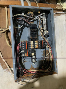 An old, rusty electrical breaker panel with exposed wiring and circuit breakers, showing a service need for KNK Electric in Pittsburgh, PA.