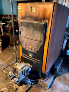 An old, rusty furnace in a basement, ready for replacement by Wilson Heating & Cooling, Inc. in North Chicago, IL.