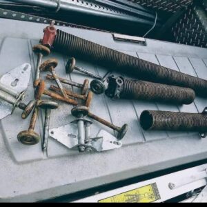 A collection of old and rusty garage door springs, rollers, and hinges, indicating parts replacement by Able Garage Door Service, LLC in Tucson, AZ.