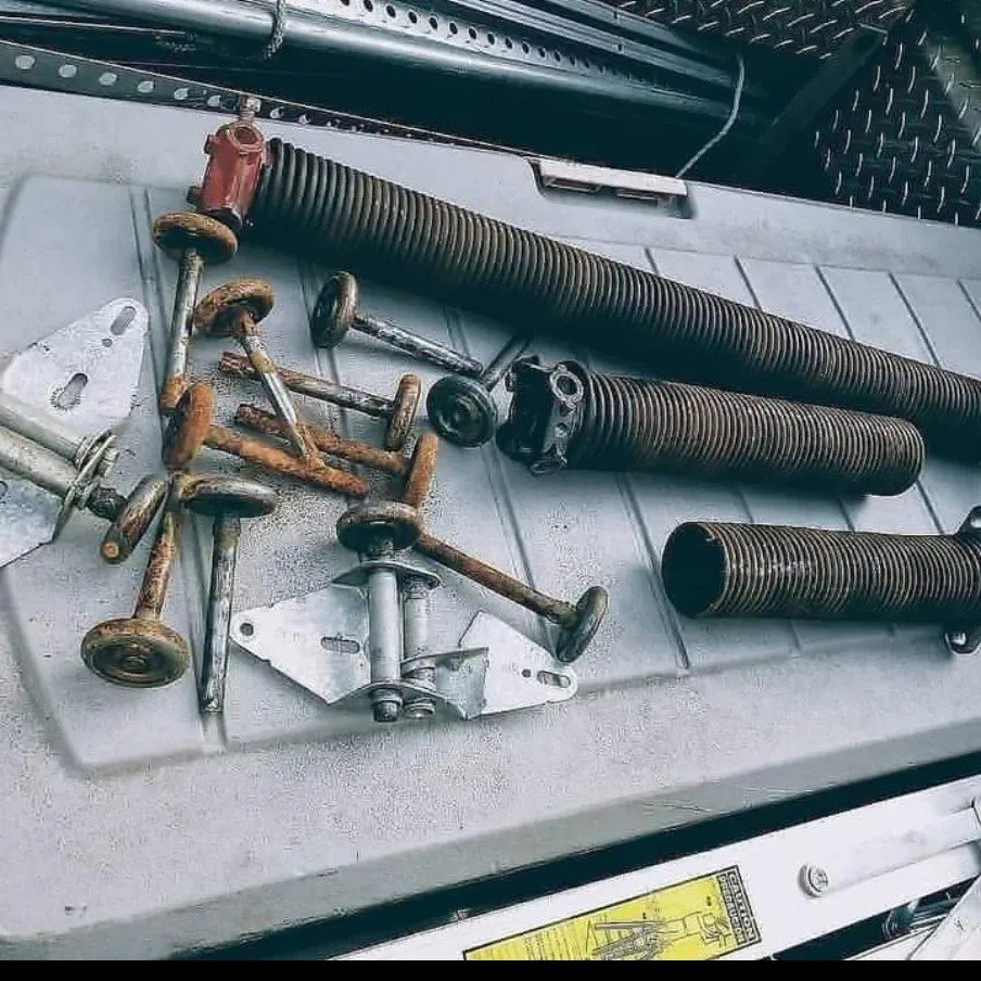 A collection of old and rusty garage door springs, rollers, and hinges, indicating parts replacement by Able Garage Door Service, LLC in Tucson, AZ.