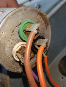 A close-up view of an old and rusty HVAC capacitor with wires, indicating a repair or replacement job by GUS' HVAC Services in Canton, GA.