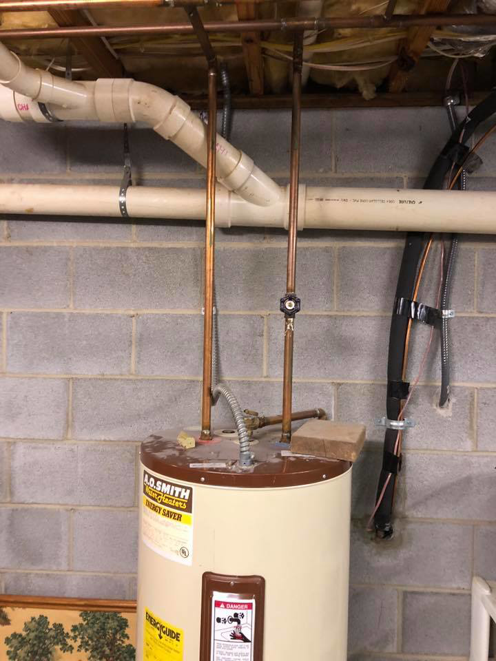 An old water heater with copper piping, ready for service or replacement by G&G Heating and Air in Portage, MI.