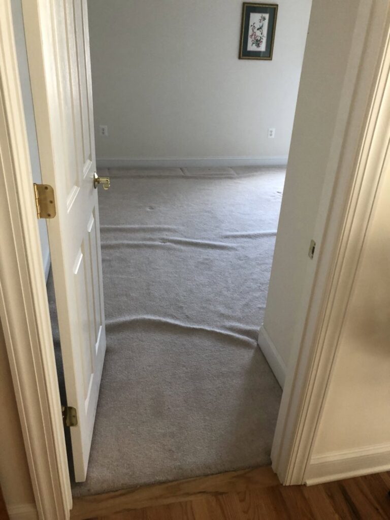 An old, wavy carpet in a room, indicating a need for repair or replacement by S&H Floor Covering in Cross Junction, VA.