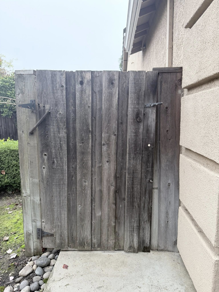 An old, weathered wooden pedestrian gate, showing a potential project for Exclusive Custom Iron Works in Stockton, CA.