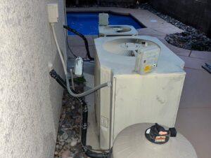 Older outdoor air conditioning units installed next to a swimming pool by The Heating & Cooling Company LLC in Las Vegas, NV.