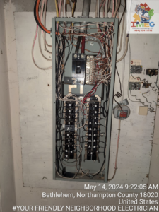 An older electrical panel with exposed wiring and breakers during an inspection or service by Imecpower in Bethlehem, PA.