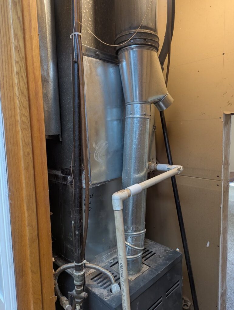 An older furnace unit and ductwork in a utility closet, serviced by I & M Heating and Cooling in South Bend, IN.