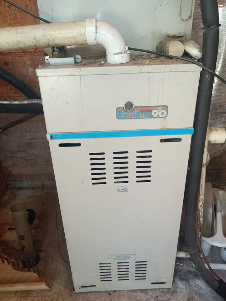 An older indoor furnace or boiler unit, indicating heating system service by Conway's Heating & Air in Concord, NC.