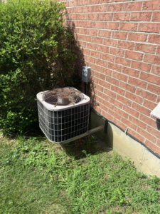 An older outdoor air conditioning condenser unit, ready for service or replacement by MK Home Services in Florence, KY.